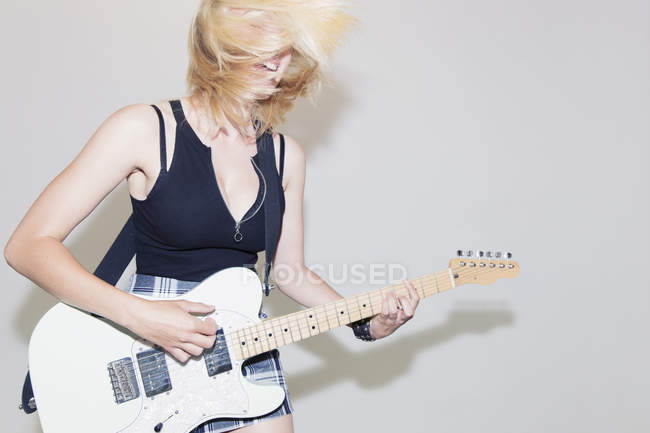 Jeune femme exubérante jouant de la guitare électrique — Photo de stock