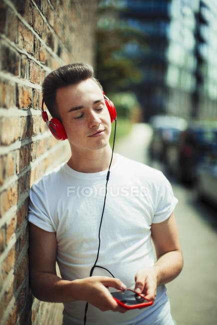 Серединна молода жінка слухає музику з навушниками та mp3 плеєром — стокове фото