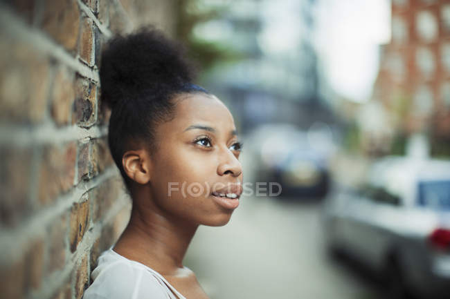 Задумчивая женщина смотрит вдаль на городской улице — стоковое фото