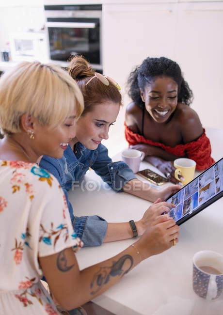 Молоді жінки друзі п'ють каву і використовують цифровий планшет — стокове фото