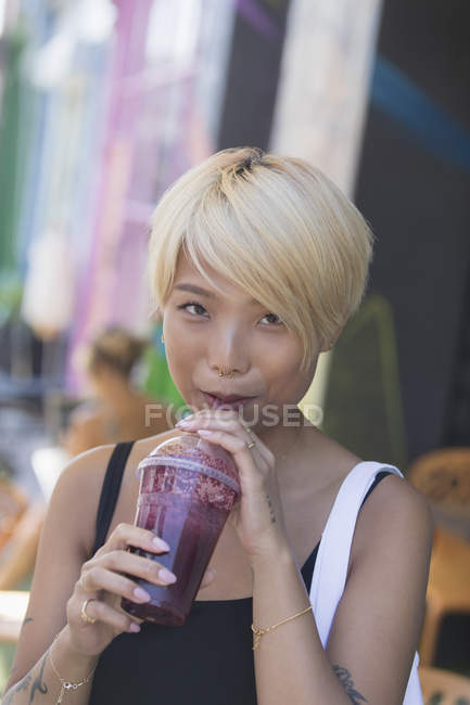 Porträt lächelnde junge Frau trinkt Smoothie — Stockfoto