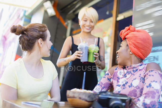 Kellnerin serviert Freundinnen Smoothies im Bürgersteig-Café — Stockfoto