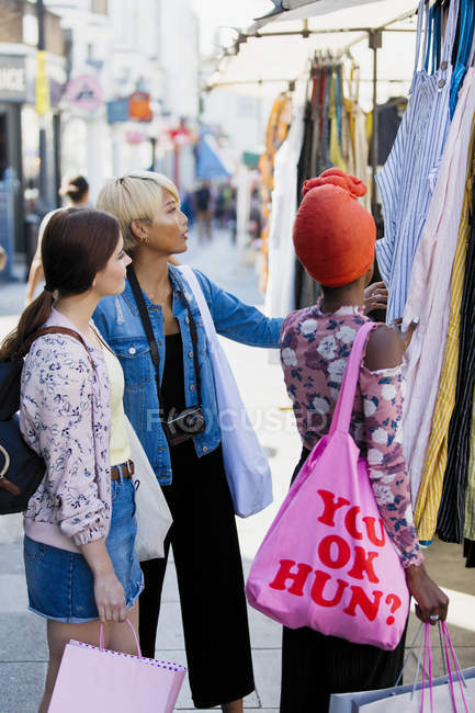 Young women friends shopping on urban sidewalk — Stock Photo