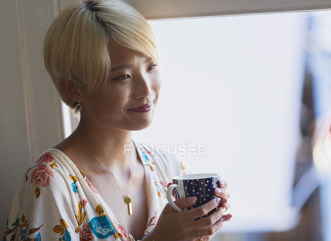 Smiling young woman drinking coffee — Stock Photo