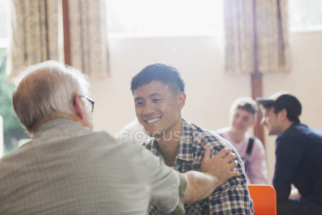 Усміхнені чоловіки розмовляють у громадському центрі — стокове фото