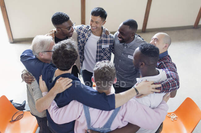 Men hugging in circle in group therapy — Stock Photo