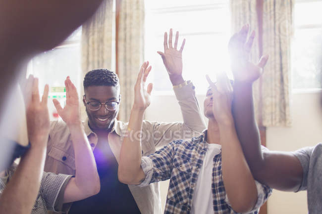 Hombres rezando con los brazos levantados en grupo de oración - foto de stock