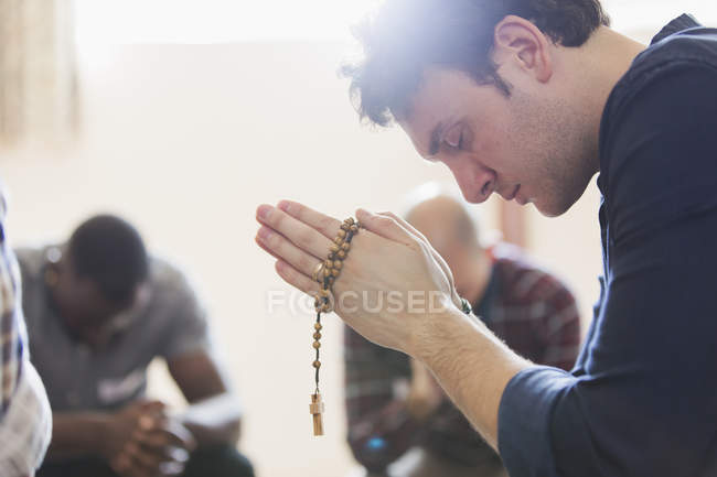 Смертельний чоловік молиться з розарієм у молитовній групі — стокове фото