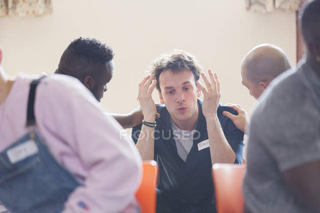 Men comforting man talking in group therapy — Stock Photo