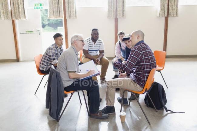 Чоловіки розмовляють по колу в груповій терапії — стокове фото