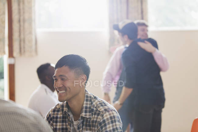 Hombre sonriente disfrutando de terapia de grupo - foto de stock