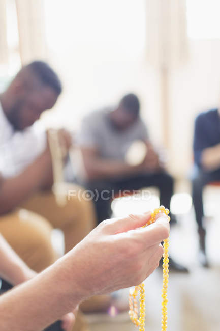 Close up man praying with rosary in prayer group — Stock Photo
