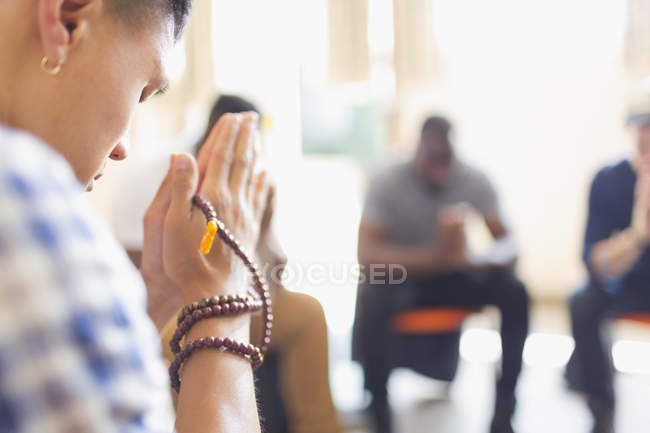 Homem orando com contas de oração em grupo de oração — Fotografia de Stock