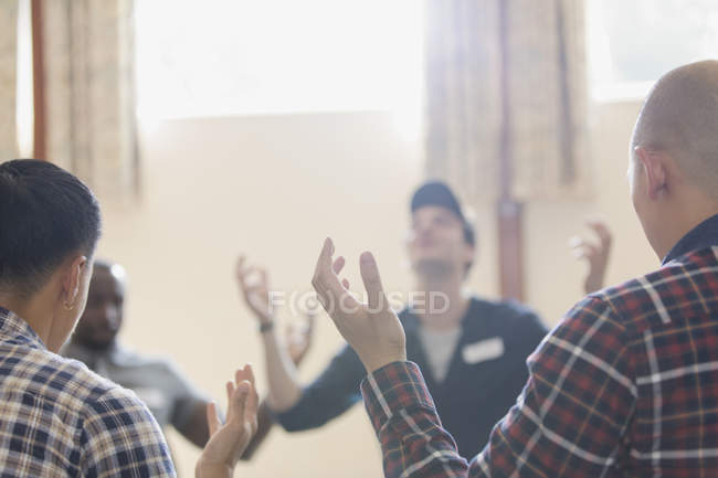 Men with arms raised praying in prayer group in community center — Stock Photo
