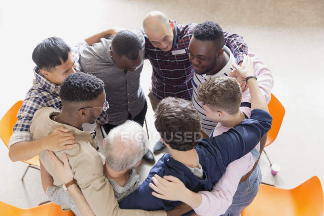 Hombres abrazándose en el abrazo en la terapia de grupo - foto de stock