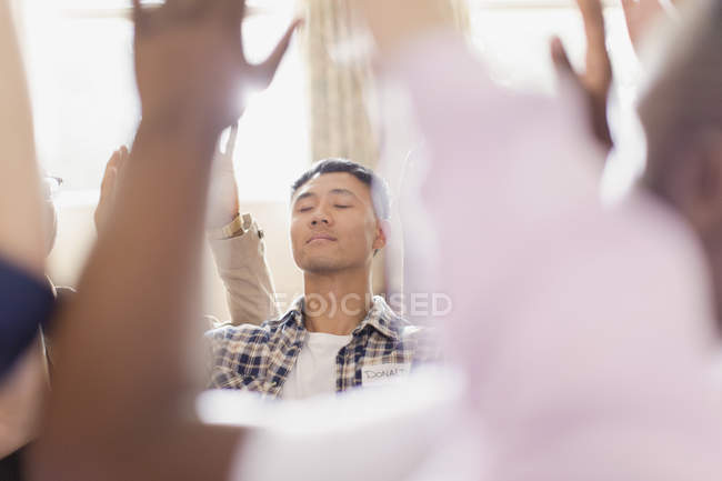 Gelassener Mann betet mit erhobenen Armen in Gebetsgruppe — Stockfoto