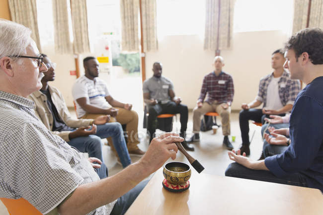 Людина використовує співочу чашу в медитаційній групі — стокове фото