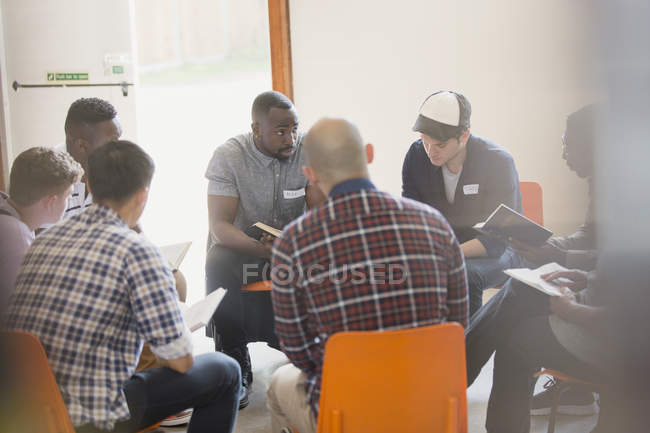 Hommes lisant et discutant la Bible en cercle dans un groupe de prière — Photo de stock