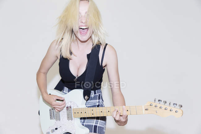 Porträt einer überschwänglichen jungen Frau, die E-Gitarre spielt — Stockfoto