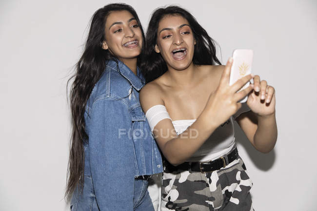 Teenage twin sisters taking selfie with smart phone — Stock Photo