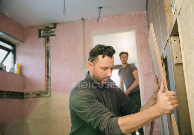 Trabalhador da construção segurando placa de madeira, casa de enquadramento — Fotografia de Stock