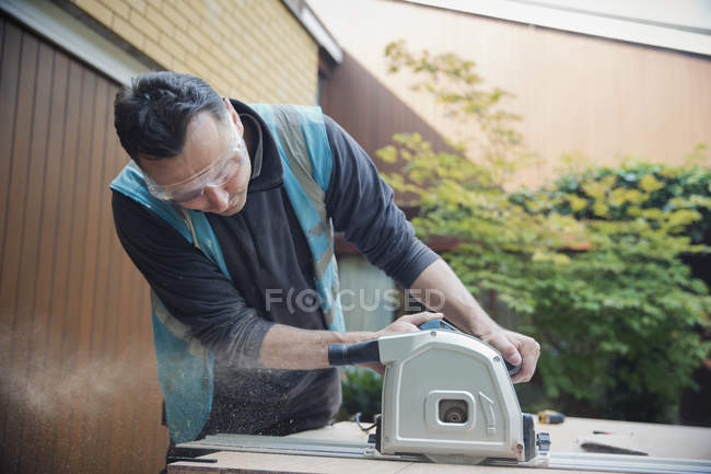 Construction worker using table saw in driveway — Stock Photo