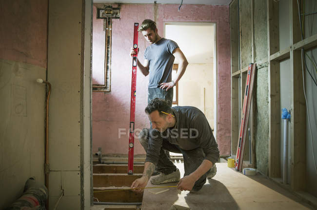 Construction workers using tape measure and level tool in house — Stock Photo