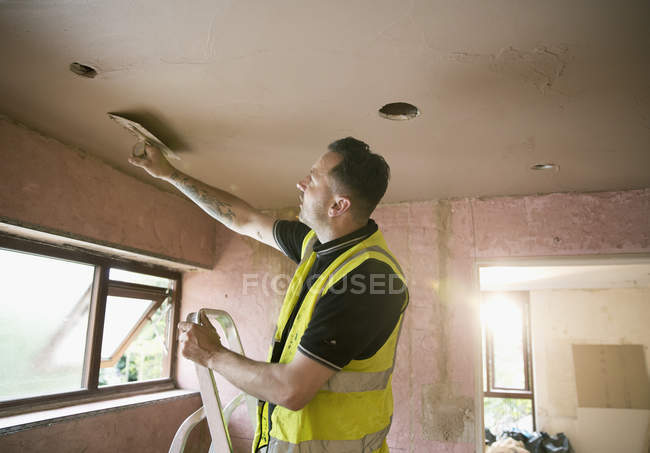 Trabajador de la construcción techo de enlucido en casa - foto de stock