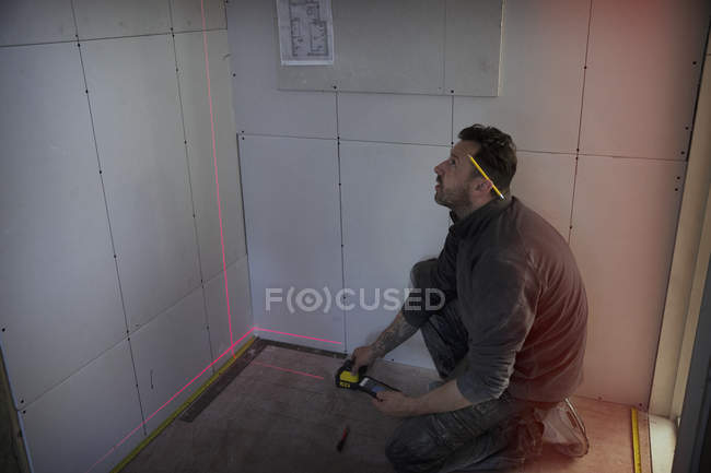 Trabalhador da construção civil usando ferramenta de medição a laser — Fotografia de Stock