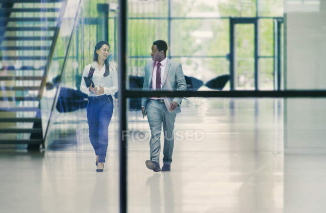 Gente de negocios caminando y hablando en el vestíbulo de oficinas - foto de stock
