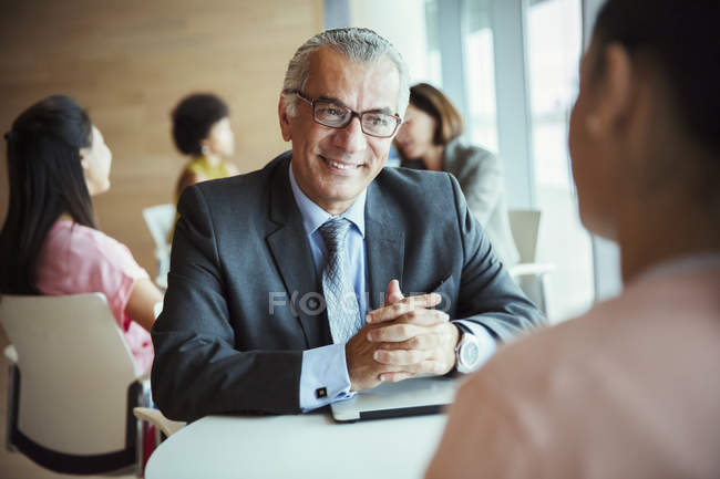 Empresário sorridente ouvindo colega na cafetaria — Fotografia de Stock