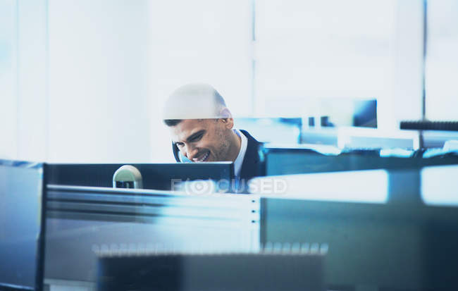 Улыбающийся бизнесмен разговаривает по телефону за компьютером в офисе — стоковое фото