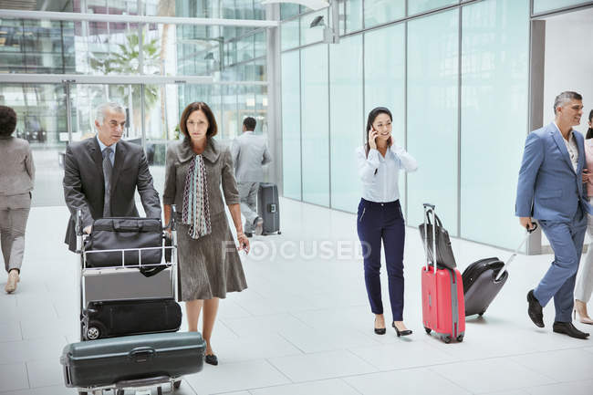 Business people with luggage in airport — Stock Photo