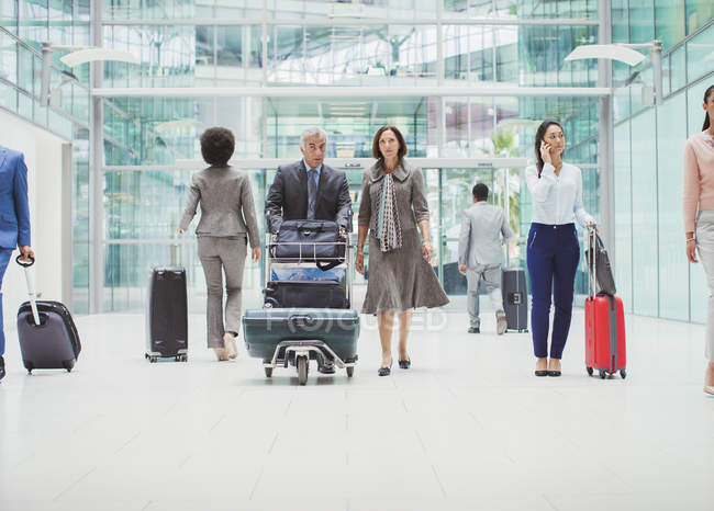 Empresários caminhando com bagagem no aeroporto — Fotografia de Stock