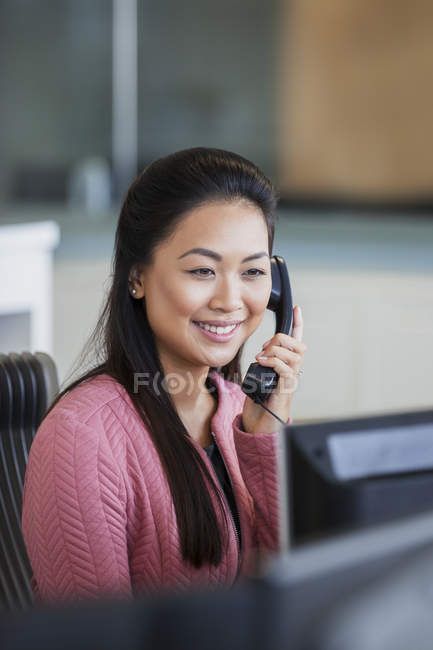 Усміхнена бізнес-леді розмовляє по телефону в офісі — стокове фото