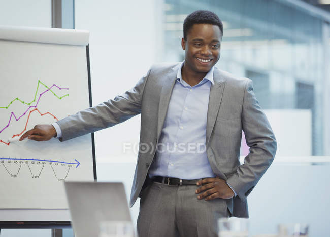 Empresário sorridente em flip chart levando reunião sala de conferências — Fotografia de Stock