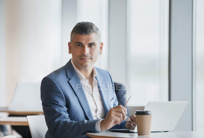 Retrato hombre de negocios seguro de trabajar en el ordenador portátil y beber café - foto de stock