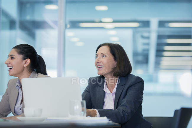 Donne d'affari sorridenti che ascoltano in sala conferenze — Foto stock