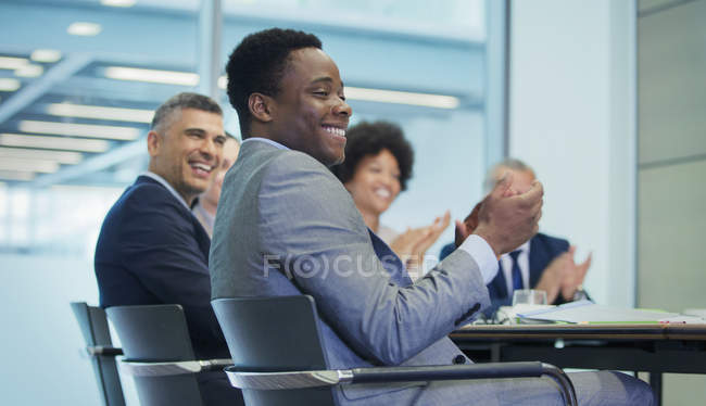 Sonriente hombre de negocios aplaudiendo en la reunión de la sala de conferencias - foto de stock