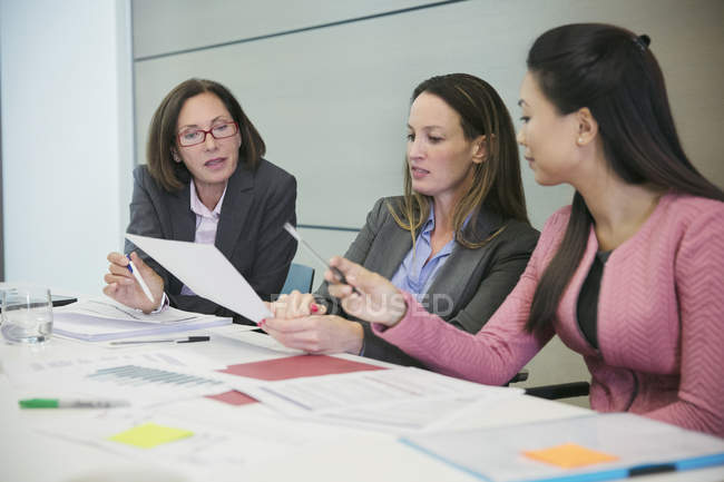 Mujeres de negocios discutiendo el papeleo en la reunión de la sala de conferencias - foto de stock