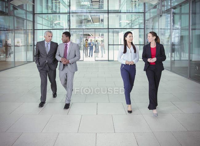 Gente de negocios caminando y hablando fuera del moderno edificio de oficinas - foto de stock