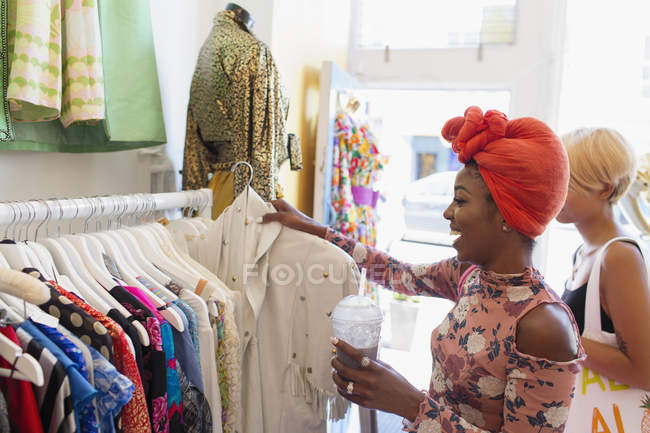 Young woman with smoothie shopping in clothing store — Stock Photo