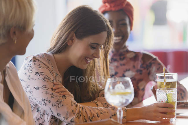 Jovens amigas rindo, bebendo coquetéis no bar — Fotografia de Stock