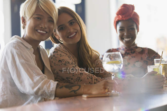 Retrato sonriente jóvenes amigas bebiendo cócteles en el bar - foto de stock
