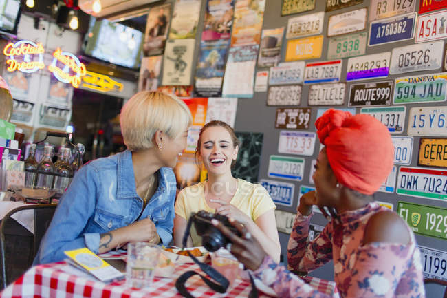 Junge Freundinnen mit Digitalkamera in Bar — Stockfoto