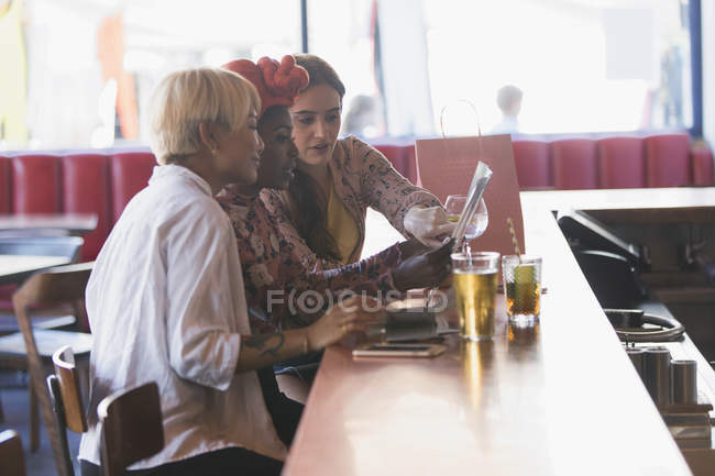 Young women friends looking at map, drinking cocktails in bar — Stock Photo