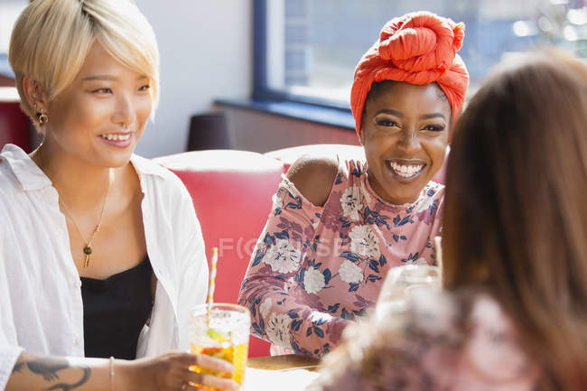 Happy young women friends drinking cocktails, talking in restaurant — Stock Photo