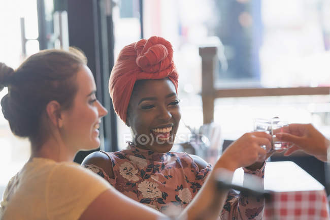 Happy young women friends taking alcohol shot in bar — Stock Photo