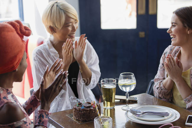 Happy young women friends celebrating birthday in restaurant — Stock Photo