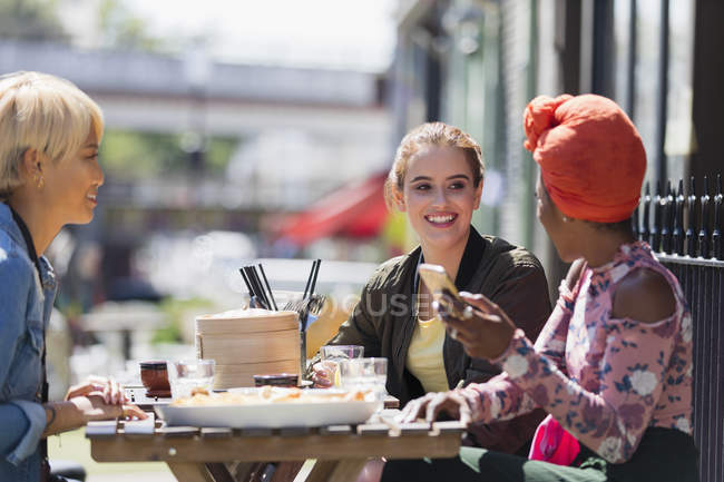 Giovani amiche godendo dim sum pranzo al sole marciapiede caffè — Foto stock